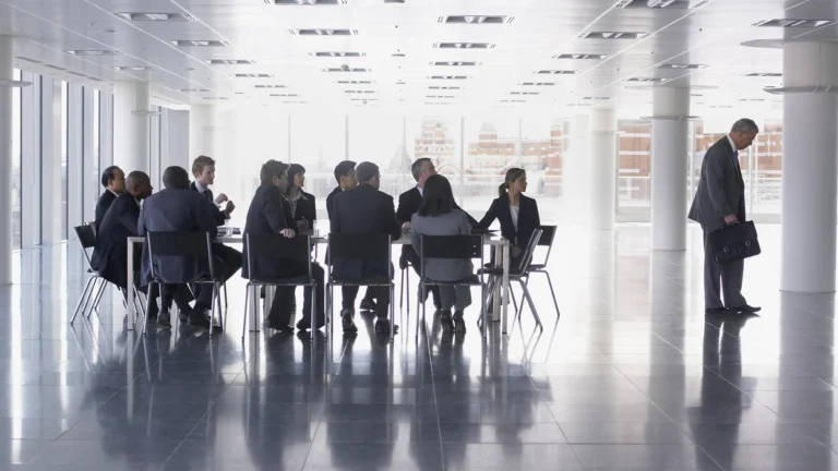 businessman-walking-away-from-colleagues-with-head-bowed-stock-photo