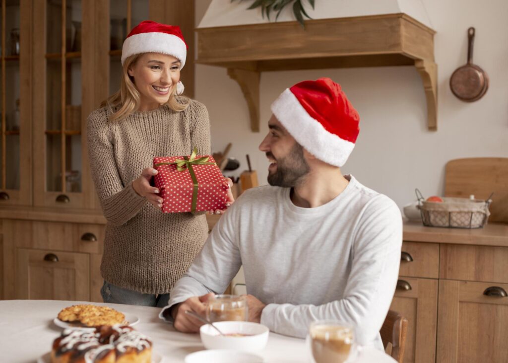 25+ Ide Hadiah Natal untuk Teman Kerja - couple wearing christmas hats indoors Ide Hadiah Natal untuk Pacar