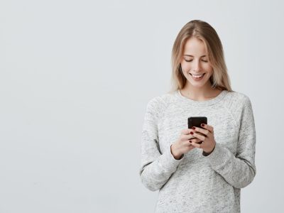 blonde-smiling-young-woman-demonstrating-white-teeth-using-cell-phone-messaging-scaled nama kontak pacar yang gak alay